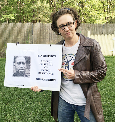 Kerry Spooner poses with a recent protest poster. 