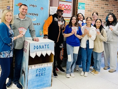 Cynthia Eaton, Denny Teason, and others posing by Eastern Campus food pantry